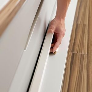 Hand opening kitchen drawer on wooden floor.